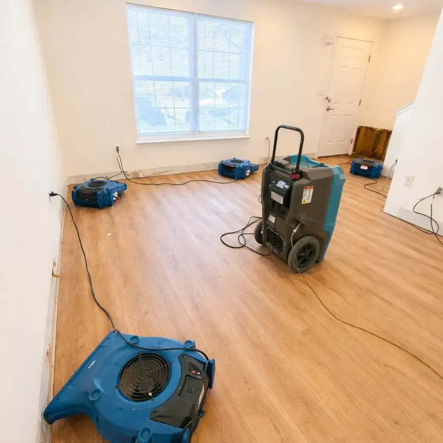 Technician setting up a red dehumidifier on a hardwood floor