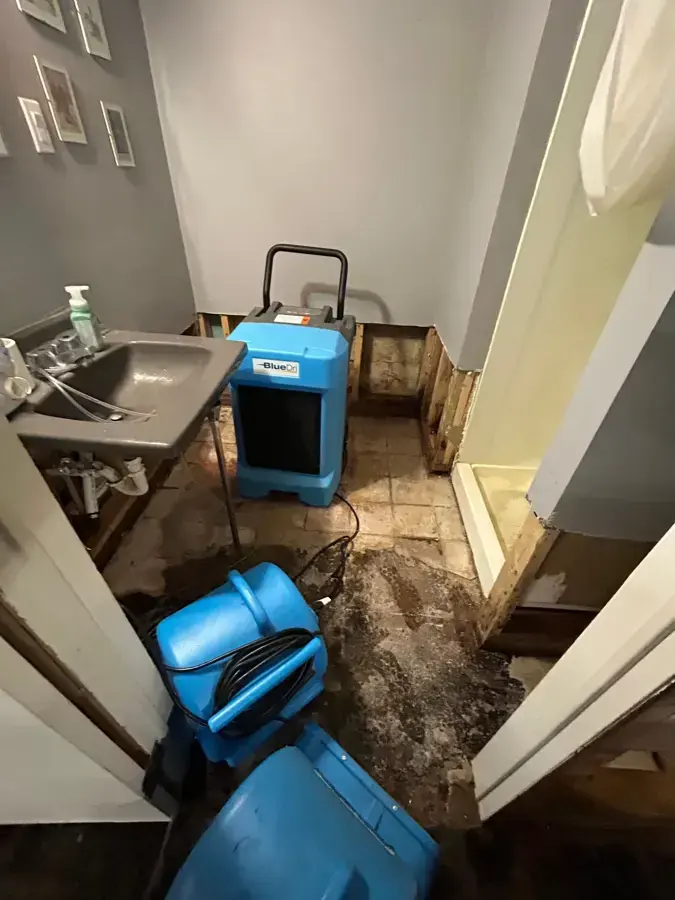 Air mover and dehumidifier drying a small bathroom with the floor opened
