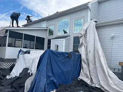 Tarps covering a damaged roof and wall after a storm