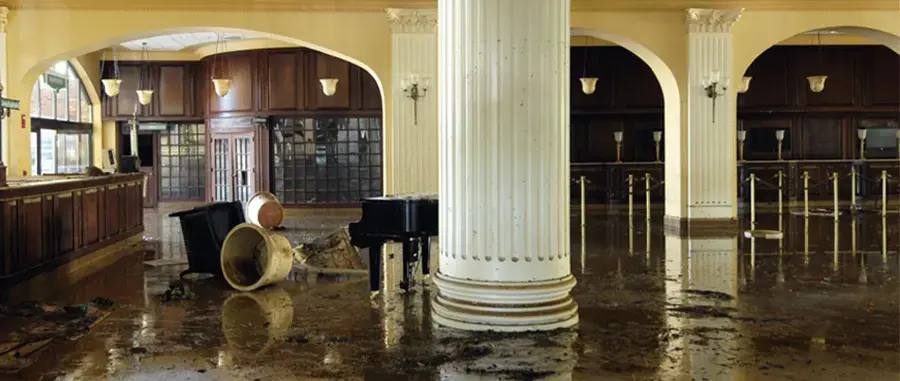 Water across the floor of an older formal room with columns and arched doorways